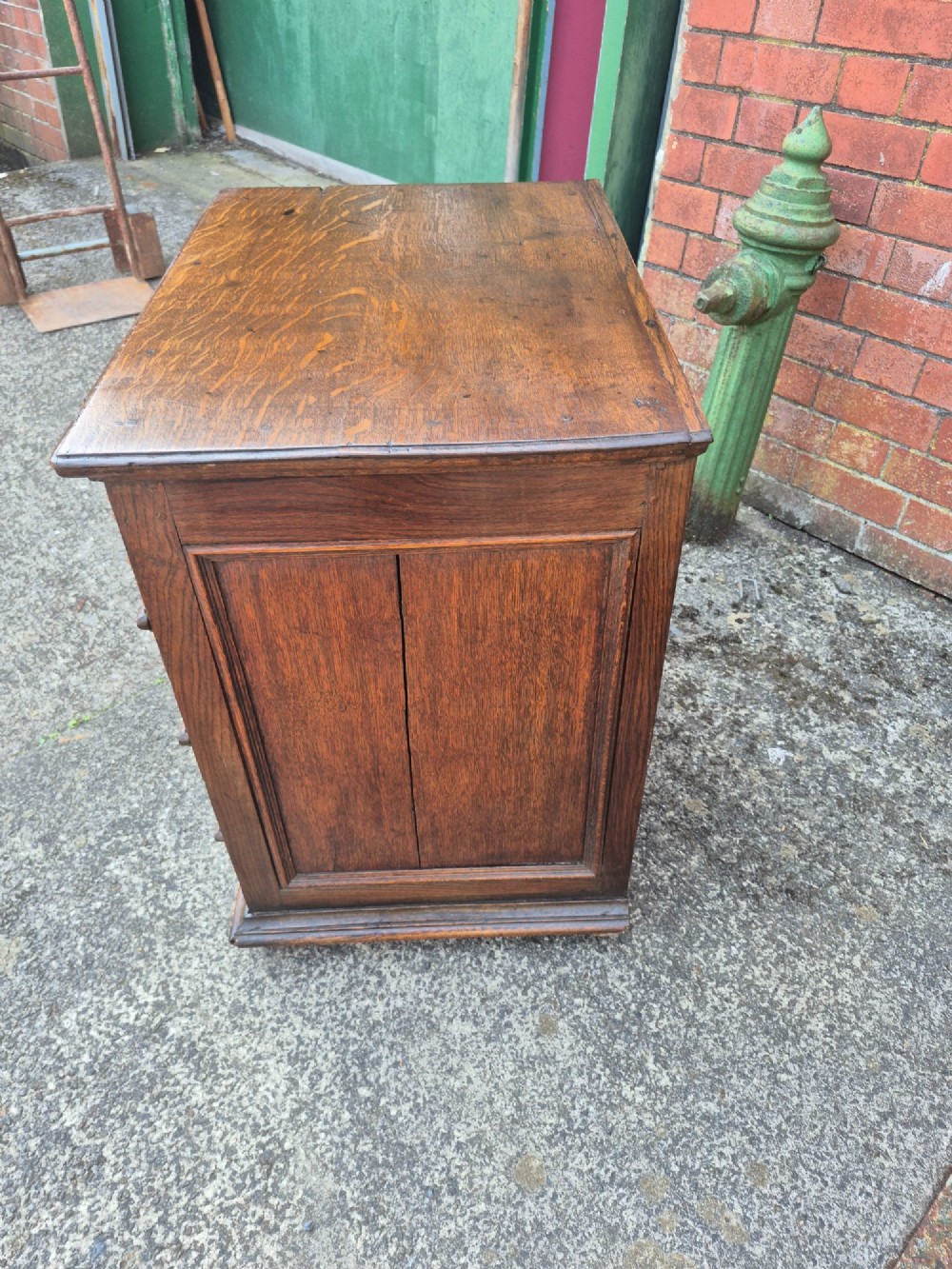 A small antique oak chest featuring four drawers with geometric moulding panels and brass drop handles. View III
