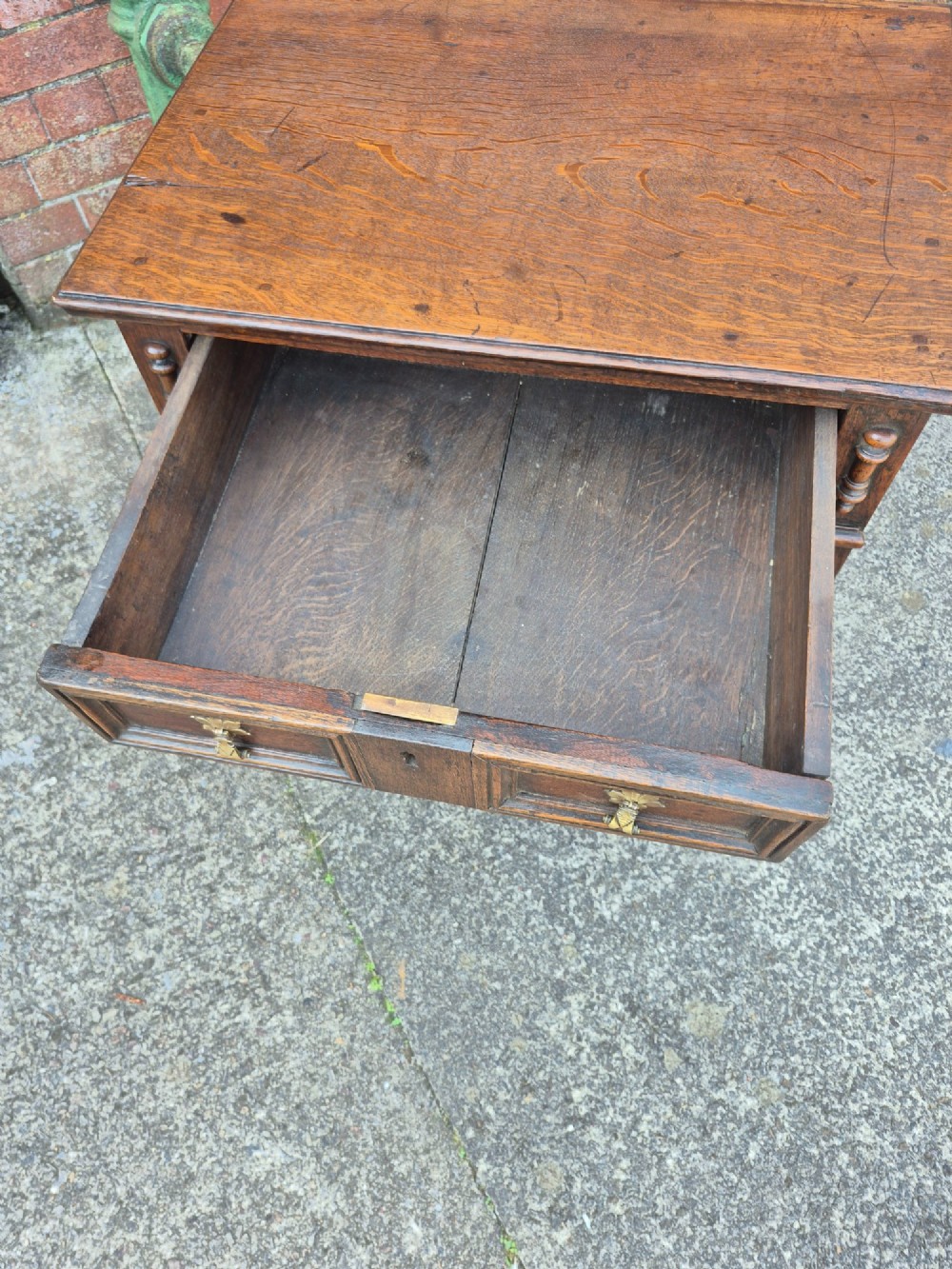 A small antique oak chest featuring four drawers with geometric moulding panels and brass drop handles. View V