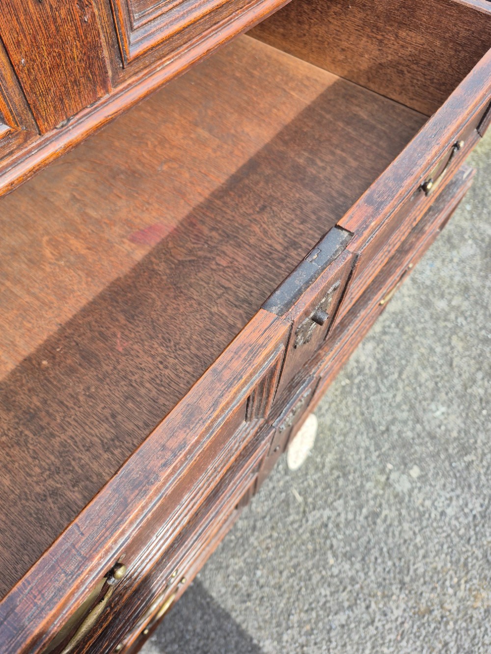 A 17th-century Charles II dark oak chest on stand featuring geometric panel mouldings, brass drop handles, and turned legs with connecting stretchers. View VII