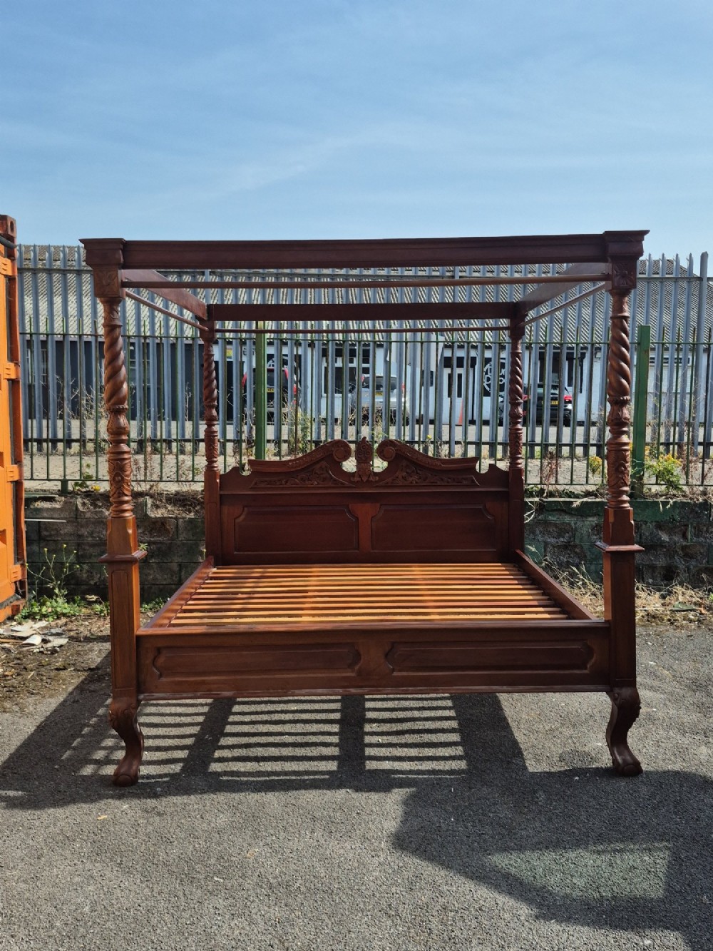 A super king size four-poster bed frame crafted from dark carved wood featuring spiral twisted posts and a scrolled headboard crest.