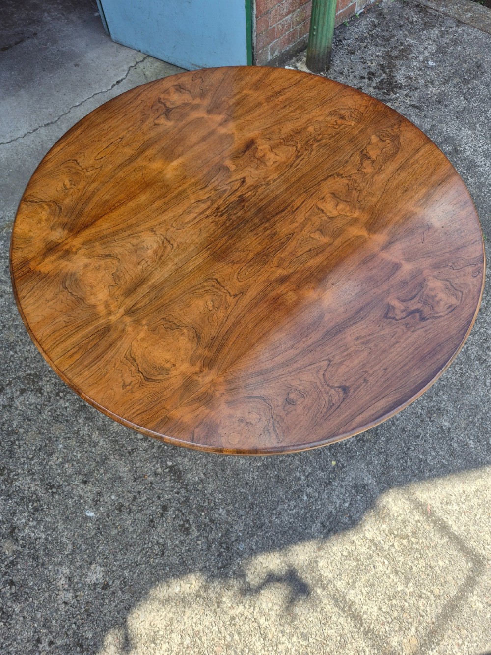 A circular Regency rosewood breakfast table featuring a figured veneer top resting on a central pedestal column with a triform base and carved feet. View VIII
