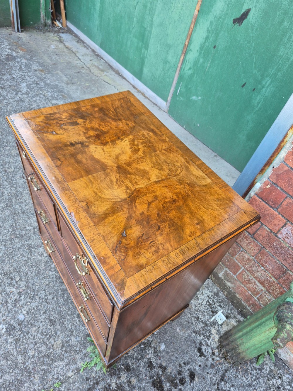 A small burr walnut bachelors chest featuring four drawers with brass handles, a brushing slide, and bracket feet. View III