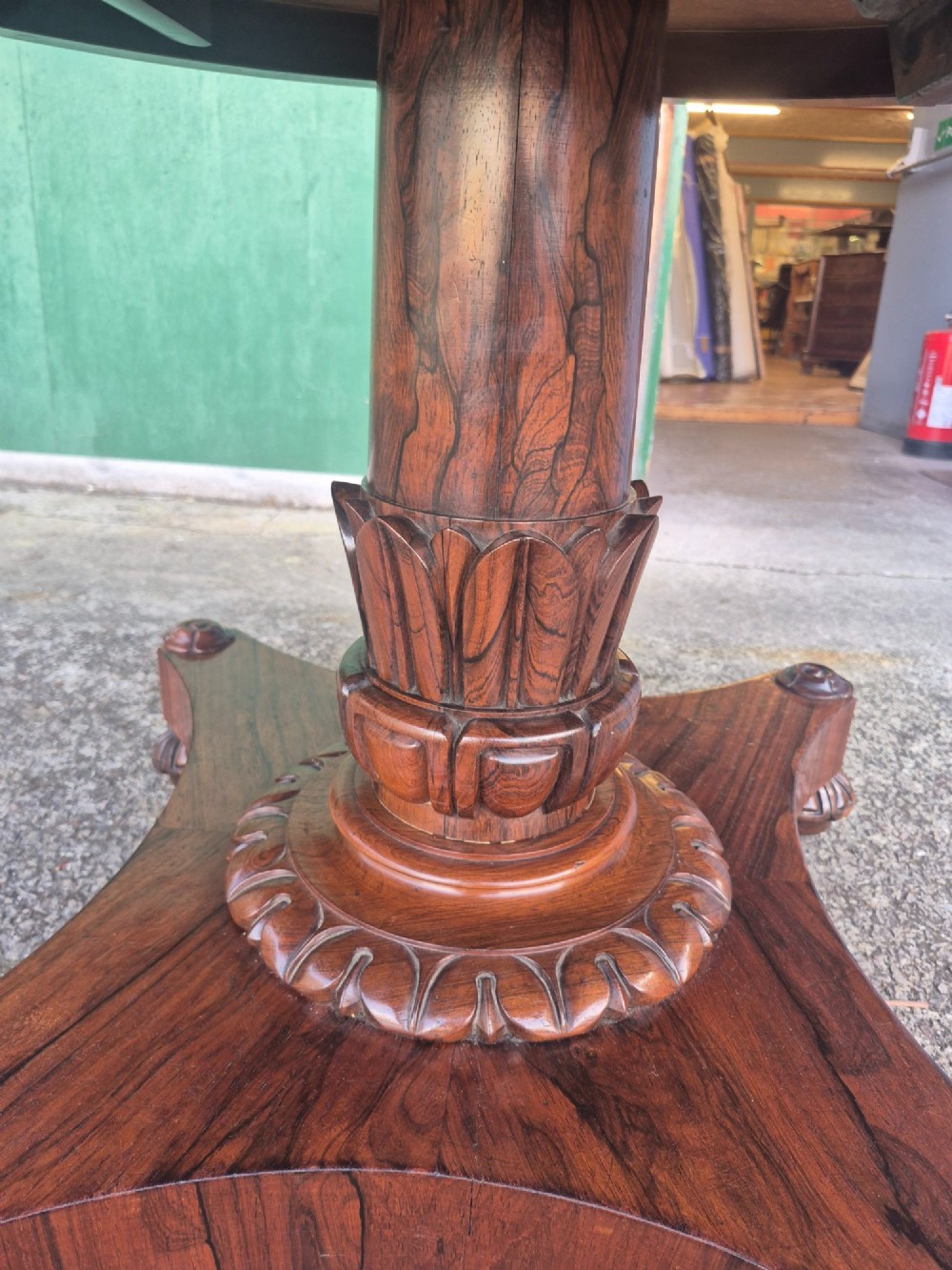 A circular Regency rosewood breakfast table featuring a figured veneer top, carved acanthus leaf pedestal column, and a concaved quadform base. View VIII