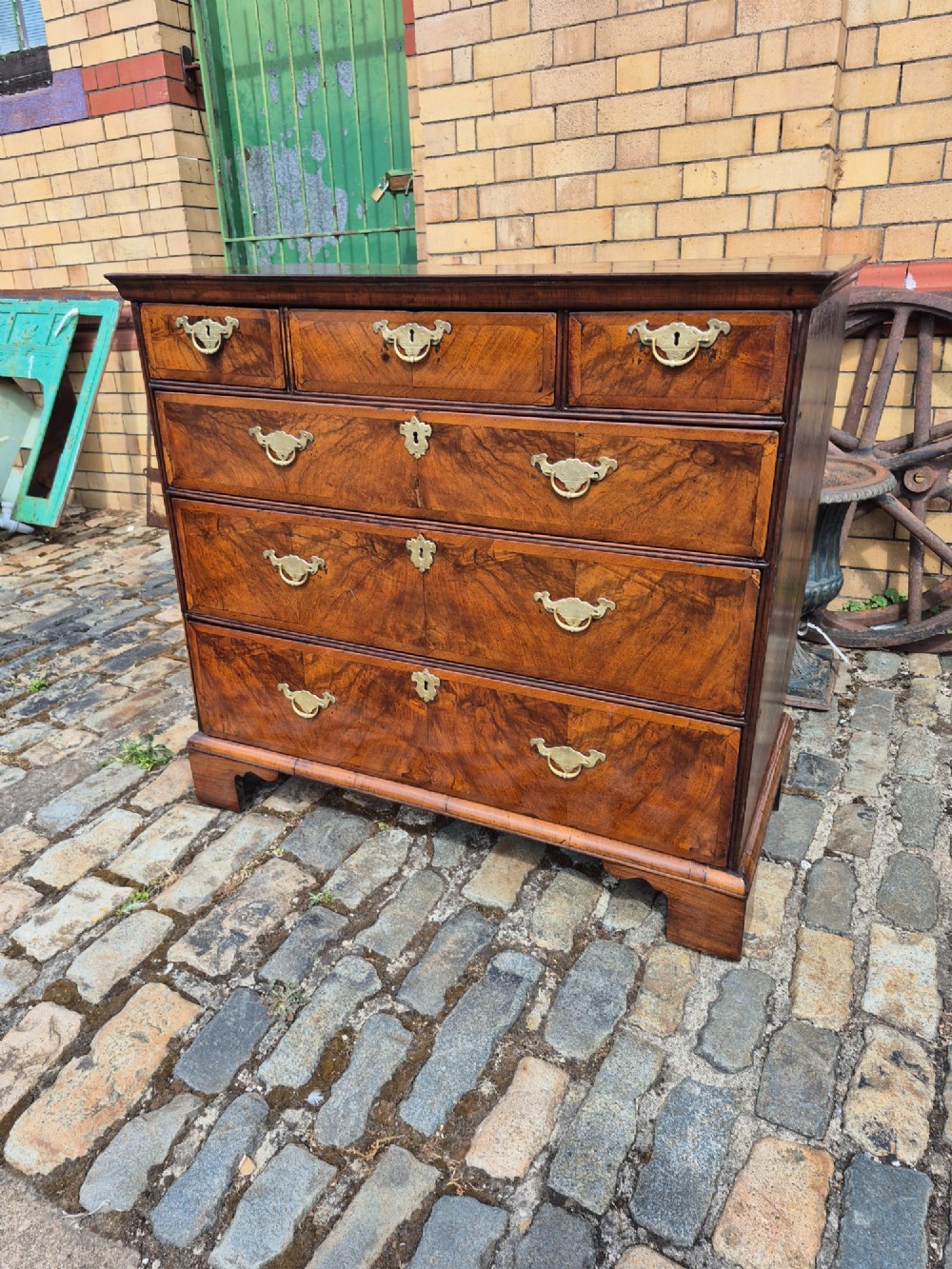A Georgian walnut and oak chest of drawers featuring three upper small drawers, three full-width lower drawers, brass handles, and bracket feet. View II