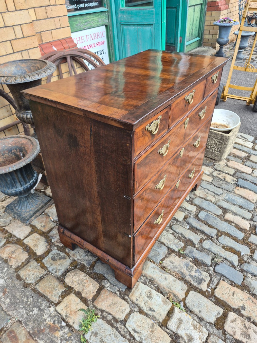 A Georgian walnut and oak chest of drawers featuring three upper small drawers, three full-width lower drawers, brass handles, and bracket feet. View IV