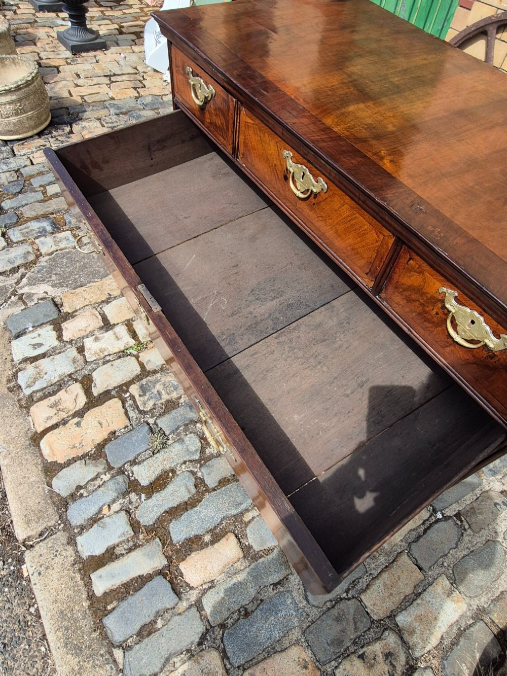 A Georgian walnut and oak chest of drawers featuring three upper small drawers, three full-width lower drawers, brass handles, and bracket feet. View VIII