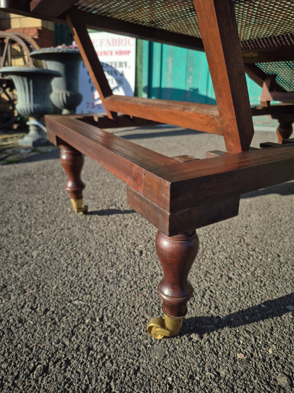 An antique campaign-style daybed crafted from dark timber with three woven cane panels, adjustable reclining sections, turned legs, and brass castors. View VI