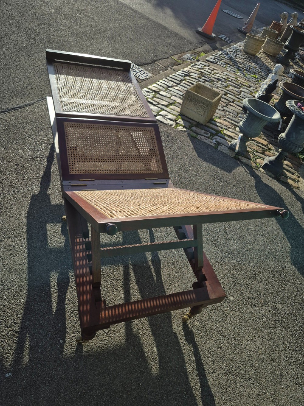 An antique campaign-style daybed crafted from dark timber with three woven cane panels, adjustable reclining sections, turned legs, and brass castors. View VIII