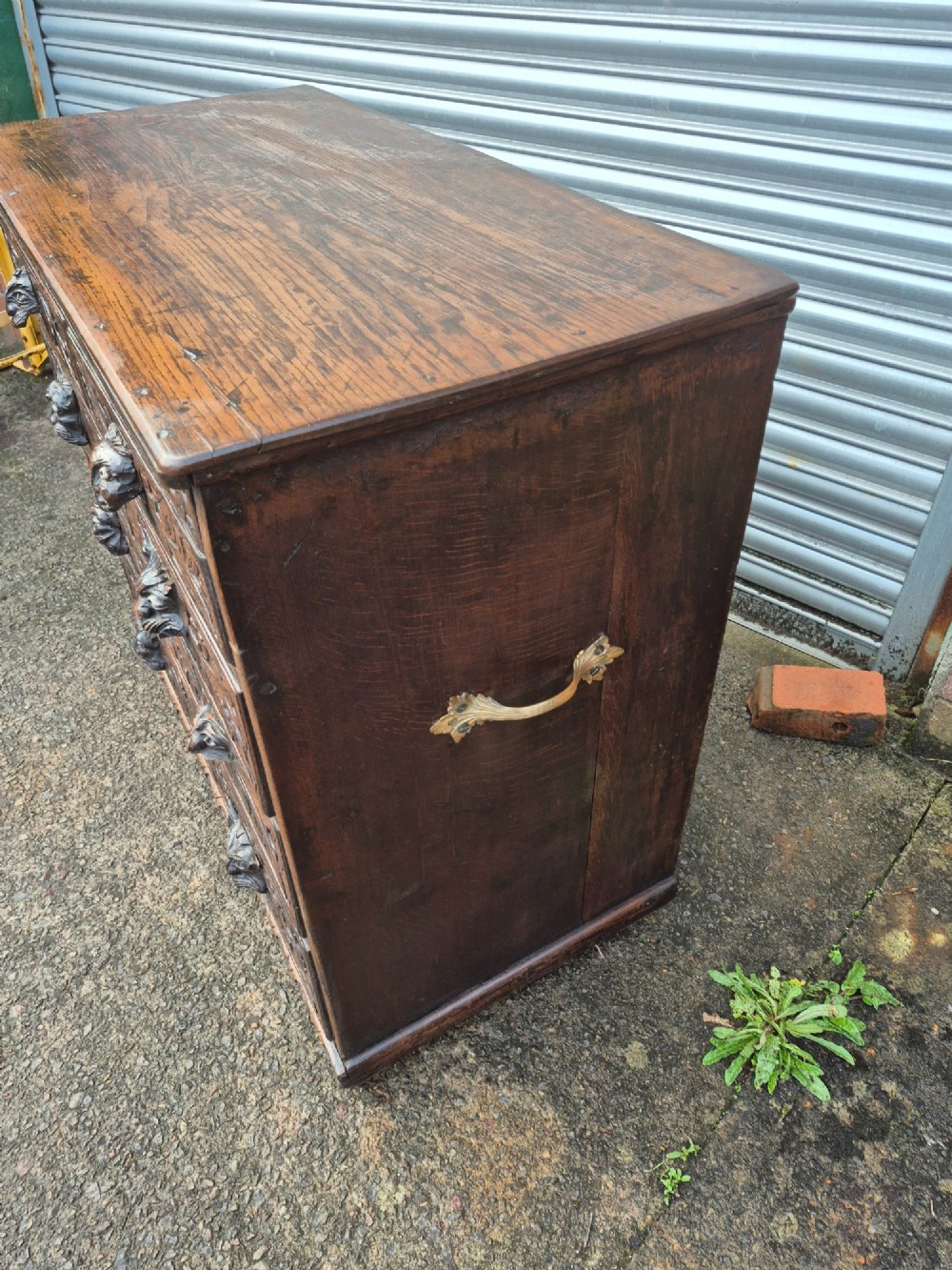A nineteenth-century dark oak chest of drawers featuring hand-carved grotesque Green Man face masks and elaborate foliate scrollwork across the front. View IX