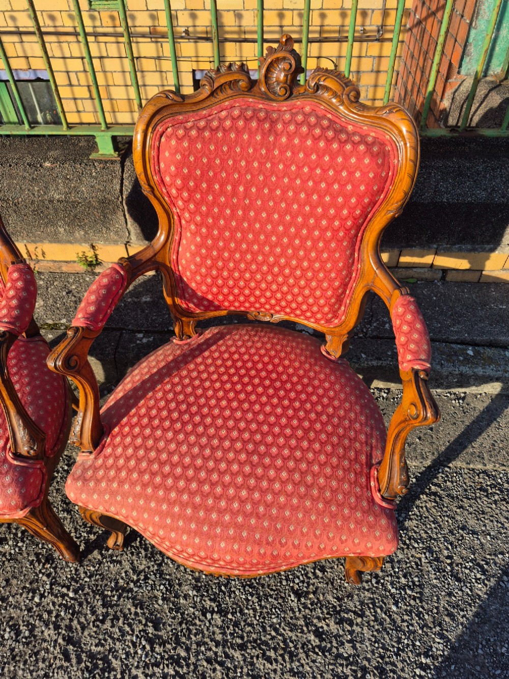 A pair of French carved walnut armchairs upholstered in patterned red fabric with cabriole legs and scrolled cresting. View II