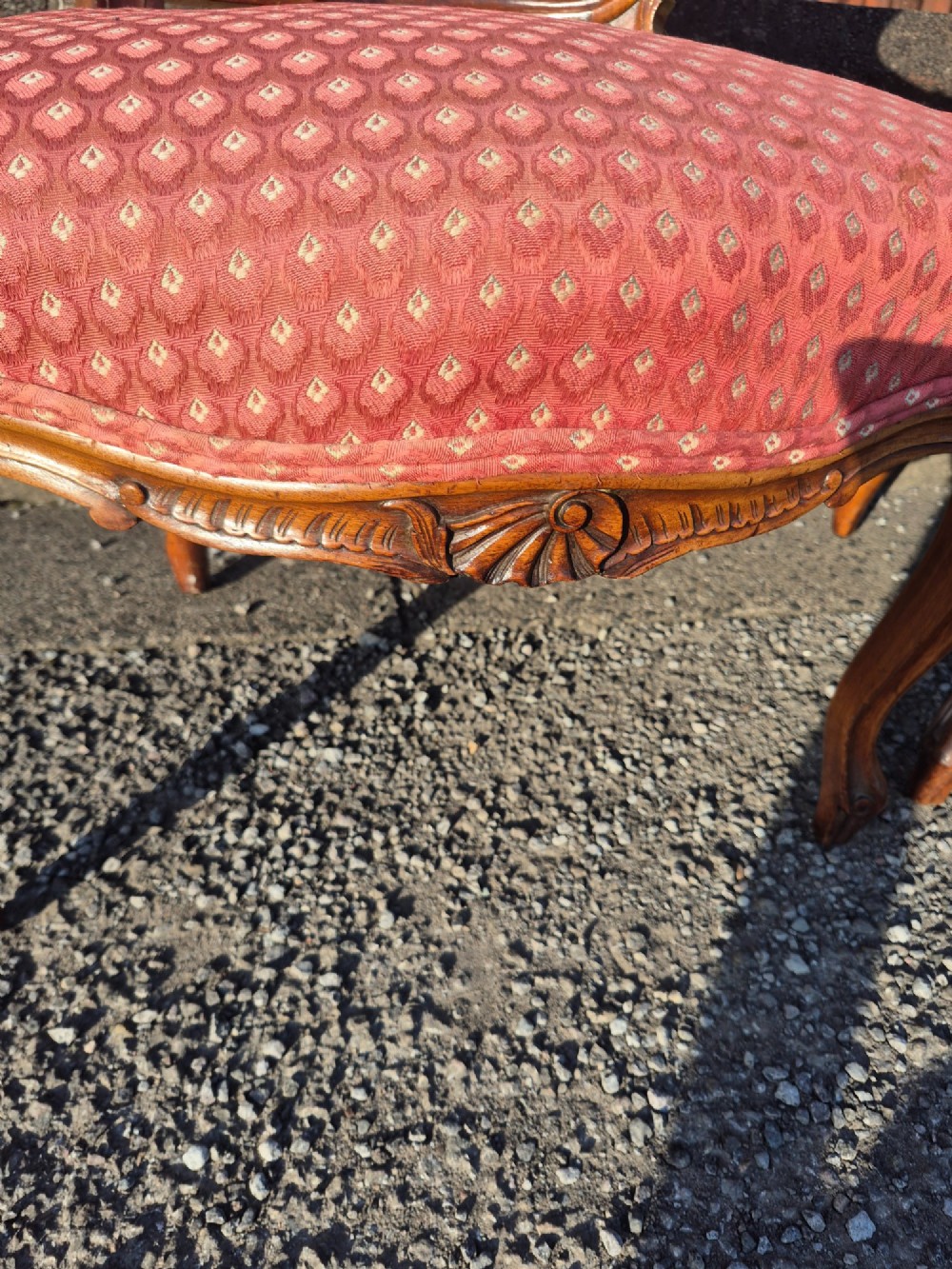 A pair of French carved walnut armchairs upholstered in patterned red fabric with cabriole legs and scrolled cresting. View IV