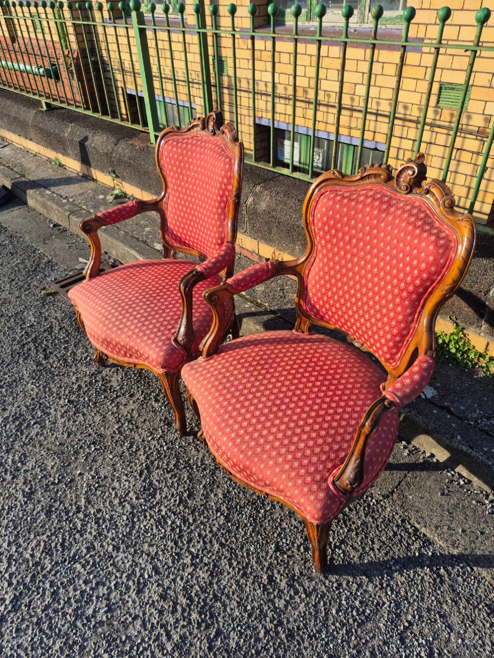 A pair of French carved walnut armchairs upholstered in patterned red fabric with cabriole legs and scrolled cresting. View V