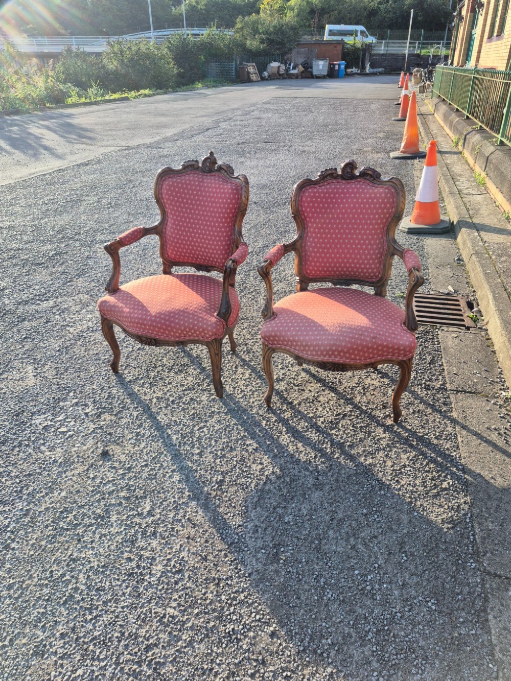 A pair of French carved walnut armchairs upholstered in patterned red fabric with cabriole legs and scrolled cresting. View VI