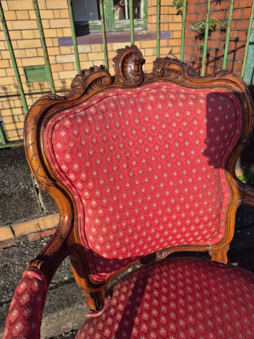 A pair of French carved walnut armchairs upholstered in patterned red fabric with cabriole legs and scrolled cresting. View IX