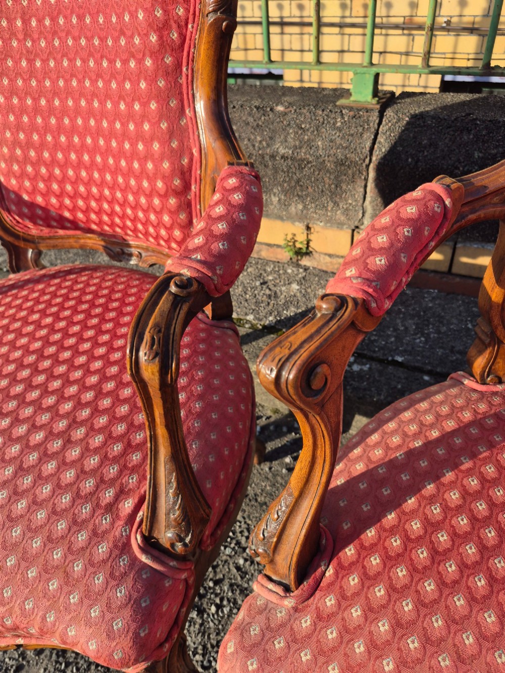 A pair of French carved walnut armchairs upholstered in patterned red fabric with cabriole legs and scrolled cresting. View X