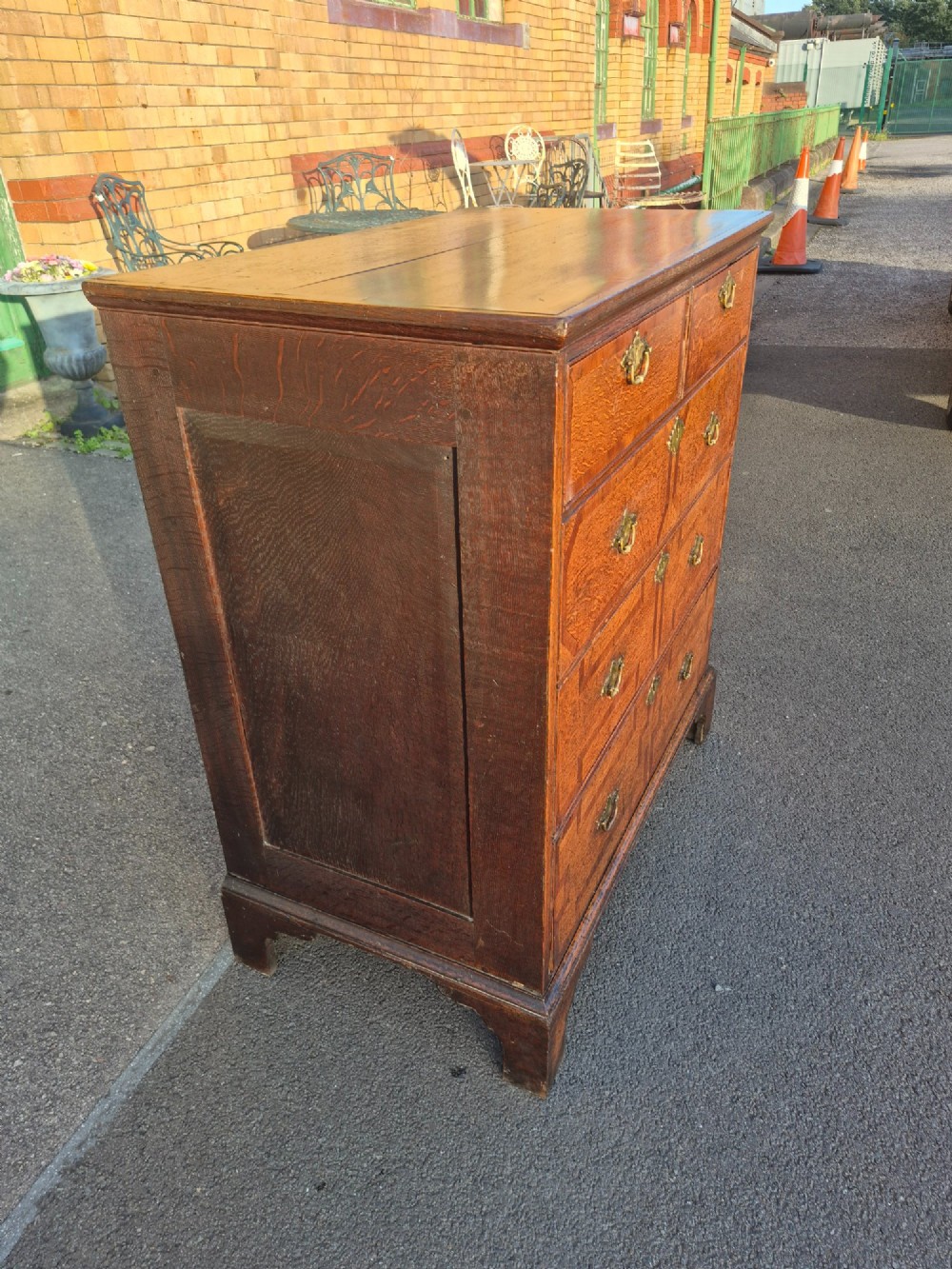 An Early Georgian oak and walnut chest of drawers featuring geometric wood banding, engraved brass handles, and bracket feet. View IV