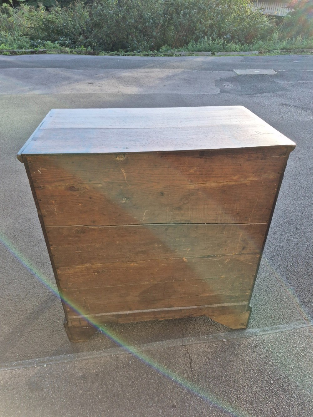 An Early Georgian oak and walnut chest of drawers featuring geometric wood banding, engraved brass handles, and bracket feet. View V