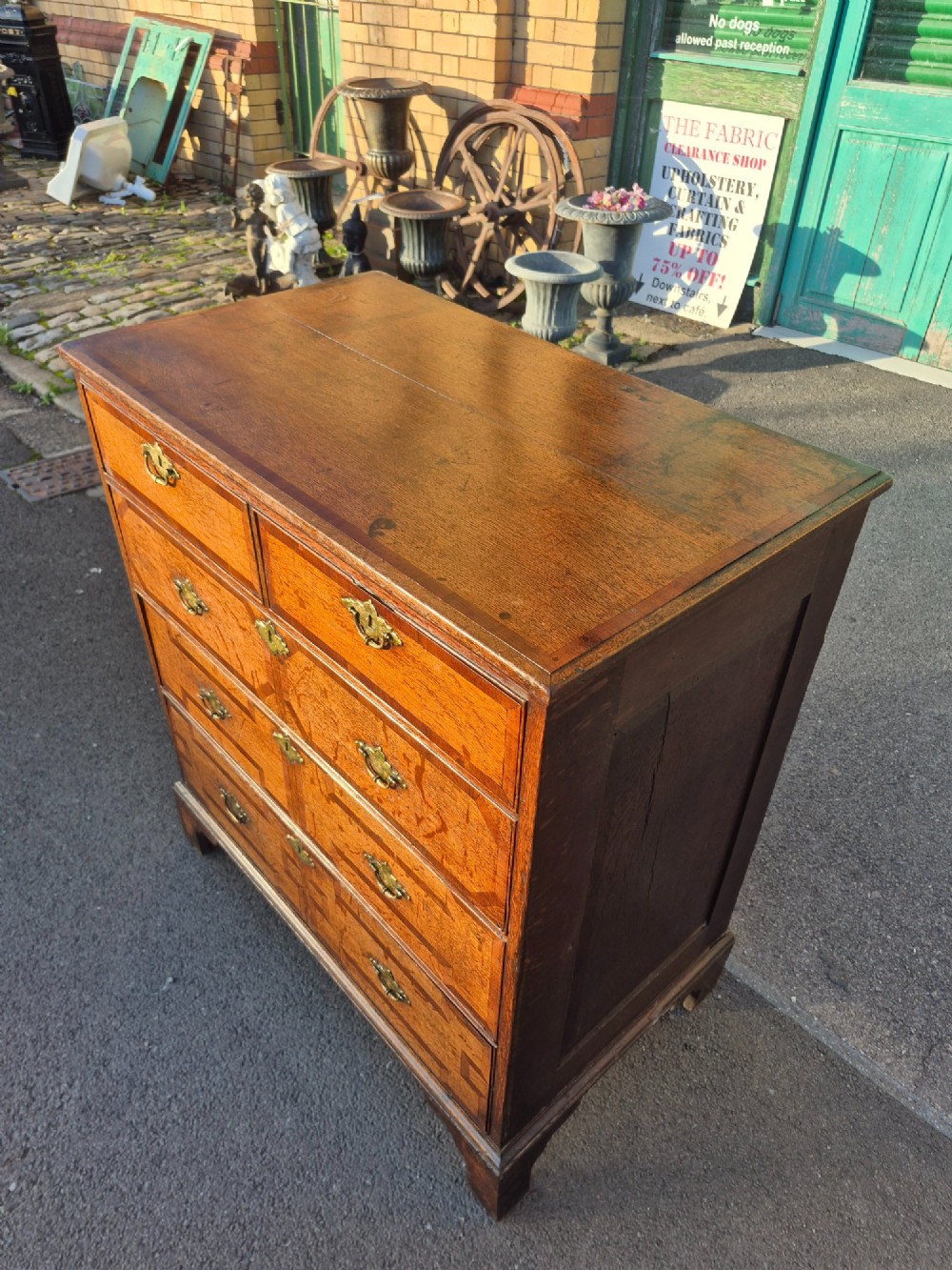 An Early Georgian oak and walnut chest of drawers featuring geometric wood banding, engraved brass handles, and bracket feet. View VII