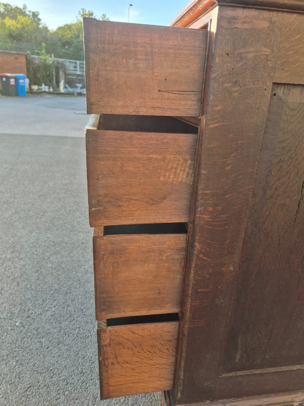 An Early Georgian oak and walnut chest of drawers featuring geometric wood banding, engraved brass handles, and bracket feet. View X