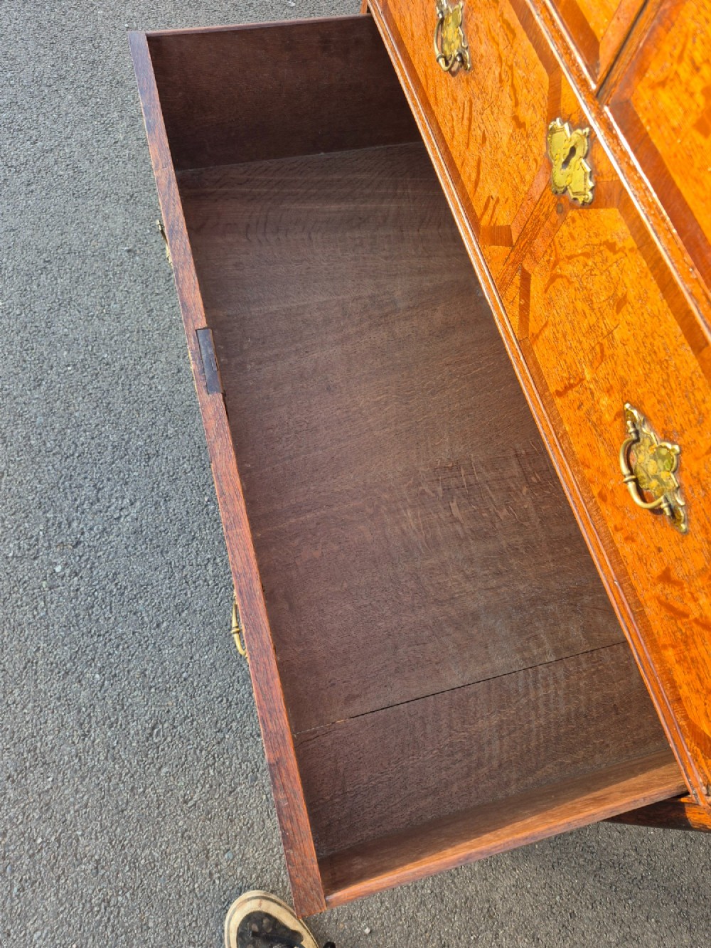 An Early Georgian oak and walnut chest of drawers featuring geometric wood banding, engraved brass handles, and bracket feet. View XI