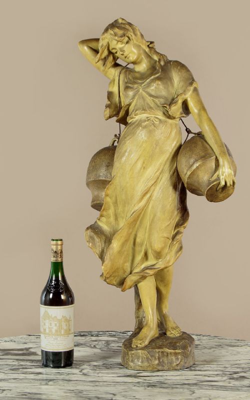 An Art Nouveau terracotta sculpture depicting a draped female water carrier holding two vessels. View II