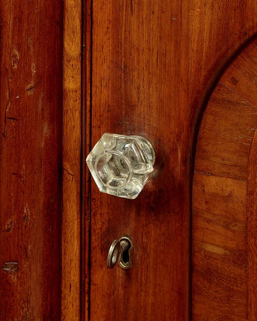 A Victorian walnut sideboard featuring a central arched cupboard door flanked by drawers with faceted glass knobs, set on turned feet. View XI