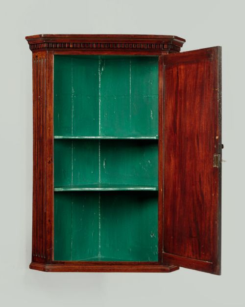 A wall-mounted Georgian mahogany corner cupboard featuring fluted pilasters, dentil moulding, and a single panelled door. View II