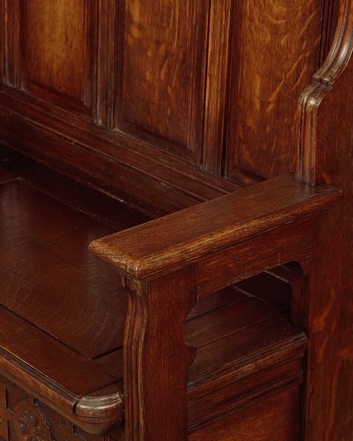 A dark oak canopy box settle featuring intricate carved floral panels, a tall fielded-panel back, and a lift-up storage seat base. View VIII
