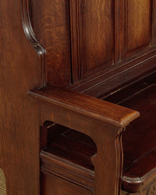 A dark oak canopy box settle featuring intricate carved floral panels, a tall fielded-panel back, and a lift-up storage seat base. View IX