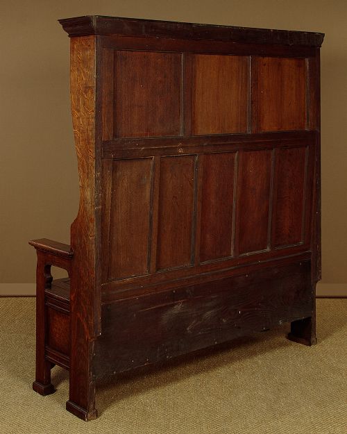 A dark oak canopy box settle featuring intricate carved floral panels, a tall fielded-panel back, and a lift-up storage seat base. View XII