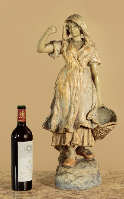 A turn-of-the-century terracotta sculpture depicting a standing young woman in rural dress wearing a headscarf and clogs, holding a basket. View II