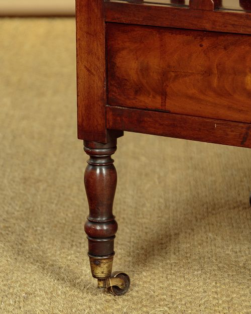 A dark mahogany Canterbury featuring four open slatted dividers above a single drawer with turned legs and brass castors. View VIII