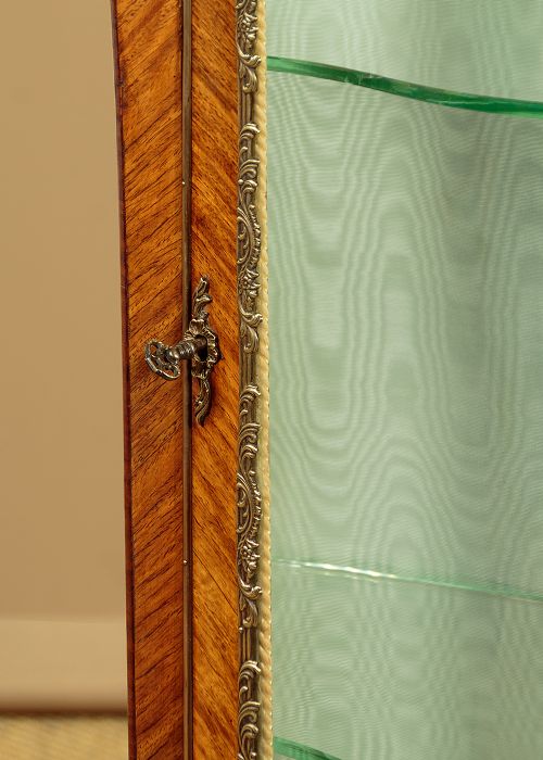 A small French Louis XV style vitrine with curved glass sides, a single glazed door, gilded brass mounts, a marble top, and a pale green fabric-lined interior with glass shelves. View X