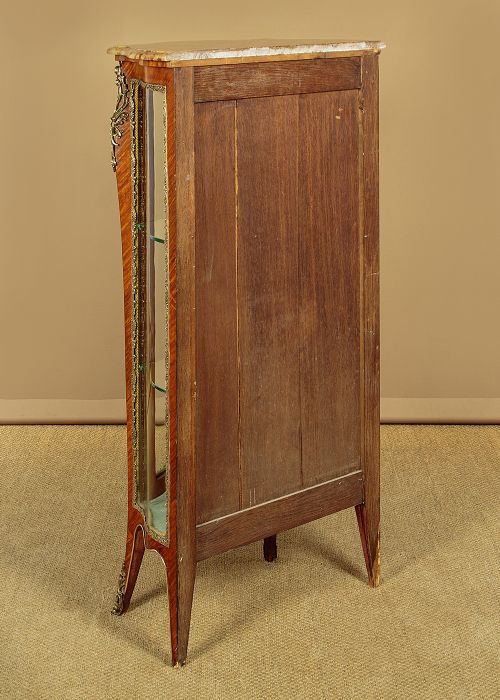 A small French Louis XV style vitrine with curved glass sides, a single glazed door, gilded brass mounts, a marble top, and a pale green fabric-lined interior with glass shelves. View XIII