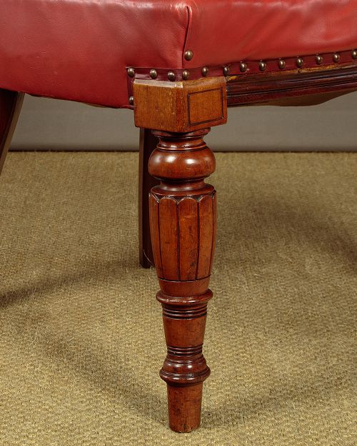 A pair of late Victorian walnut tub armchairs with red leather upholstery, studded brass trim, turned front legs, and carved scroll arm supports. View XI