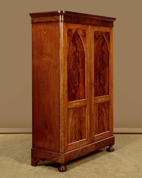 A mid-19th century compact Victorian mahogany wardrobe with flame mahogany arched door panels and round bun feet. View III