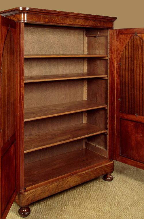 A mid-19th century compact Victorian mahogany wardrobe with flame mahogany arched door panels and round bun feet. View VIII