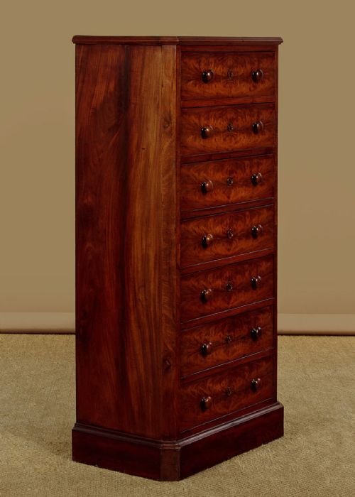 A tall and narrow Victorian mahogany bank of seven graduated drawers featuring flame mahogany veneer fronts, turned wood knob handles, and a solid plinth base. View II