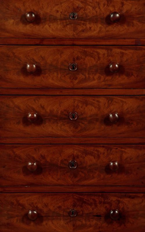 A tall and narrow Victorian mahogany bank of seven graduated drawers featuring flame mahogany veneer fronts, turned wood knob handles, and a solid plinth base. View VI