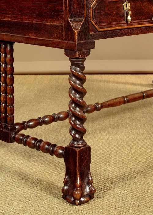 A dark carved oak writing desk featuring four geometric drawers, a scroll-carved central frieze, barley-twist legs, and a stretcher base. View XI