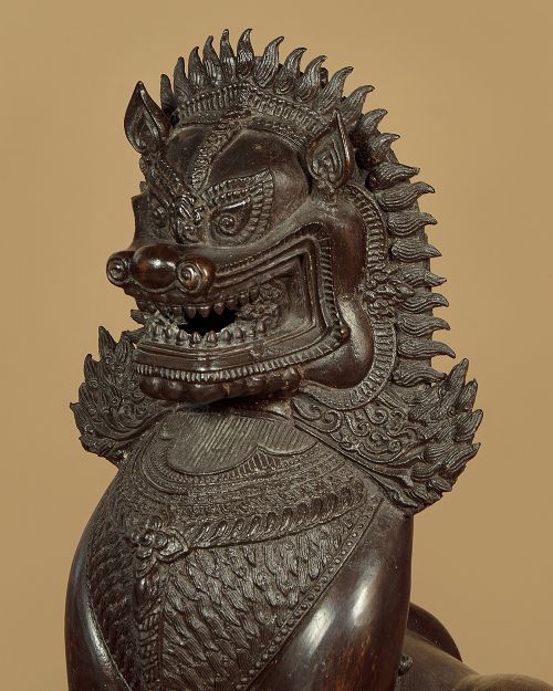 A pair of dark bronze temple lion statues sitting upright with intricate stylized manes and detailed ornamental chest bands. View VII