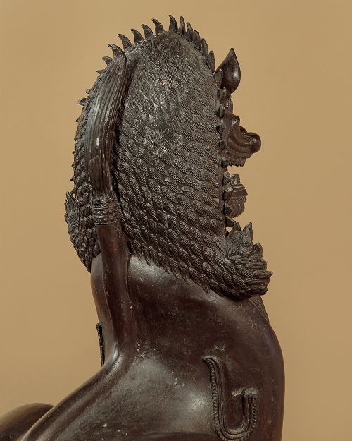 A pair of dark bronze temple lion statues sitting upright with intricate stylized manes and detailed ornamental chest bands. View X