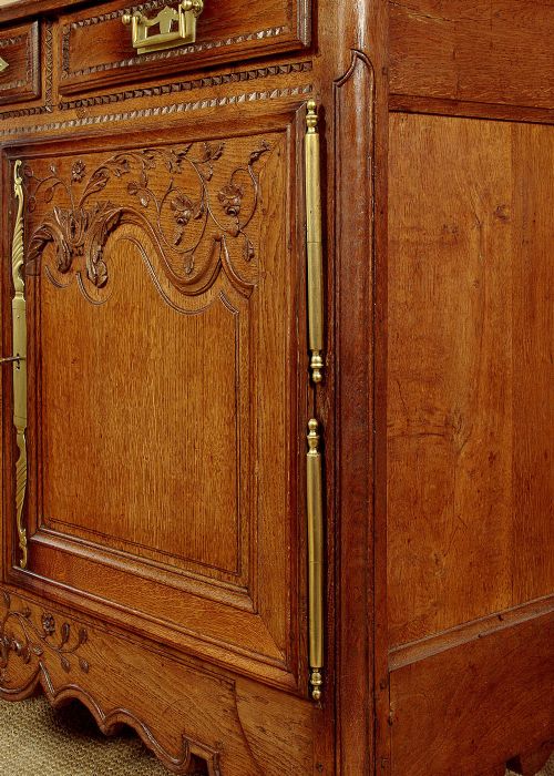 A late 18th-century French oak dresser base featuring two drawers above carved panelled cupboard doors with brass hardware. View XI