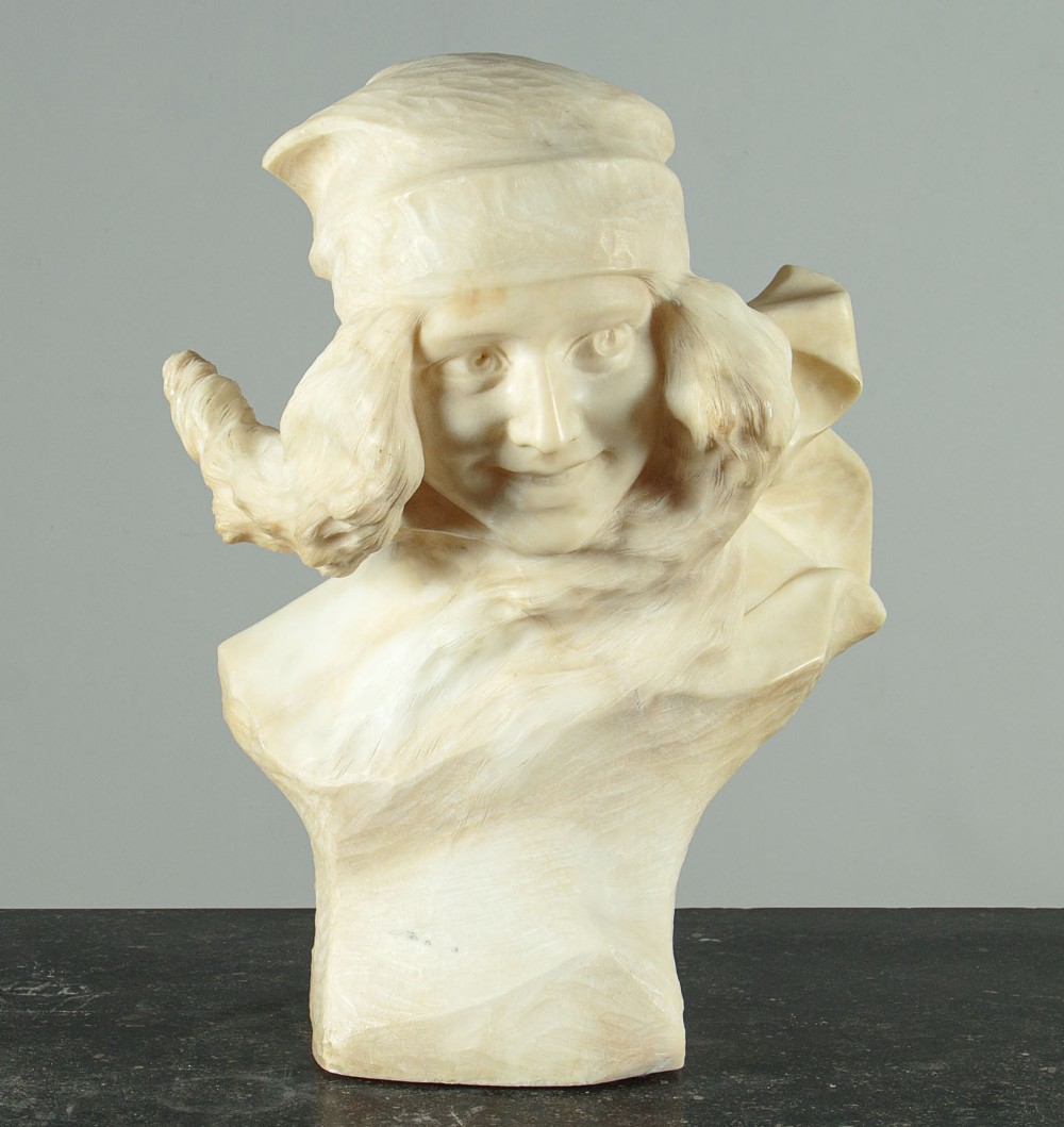A carved cream-coloured alabaster bust depicting a young girl wearing a hat and scarf.