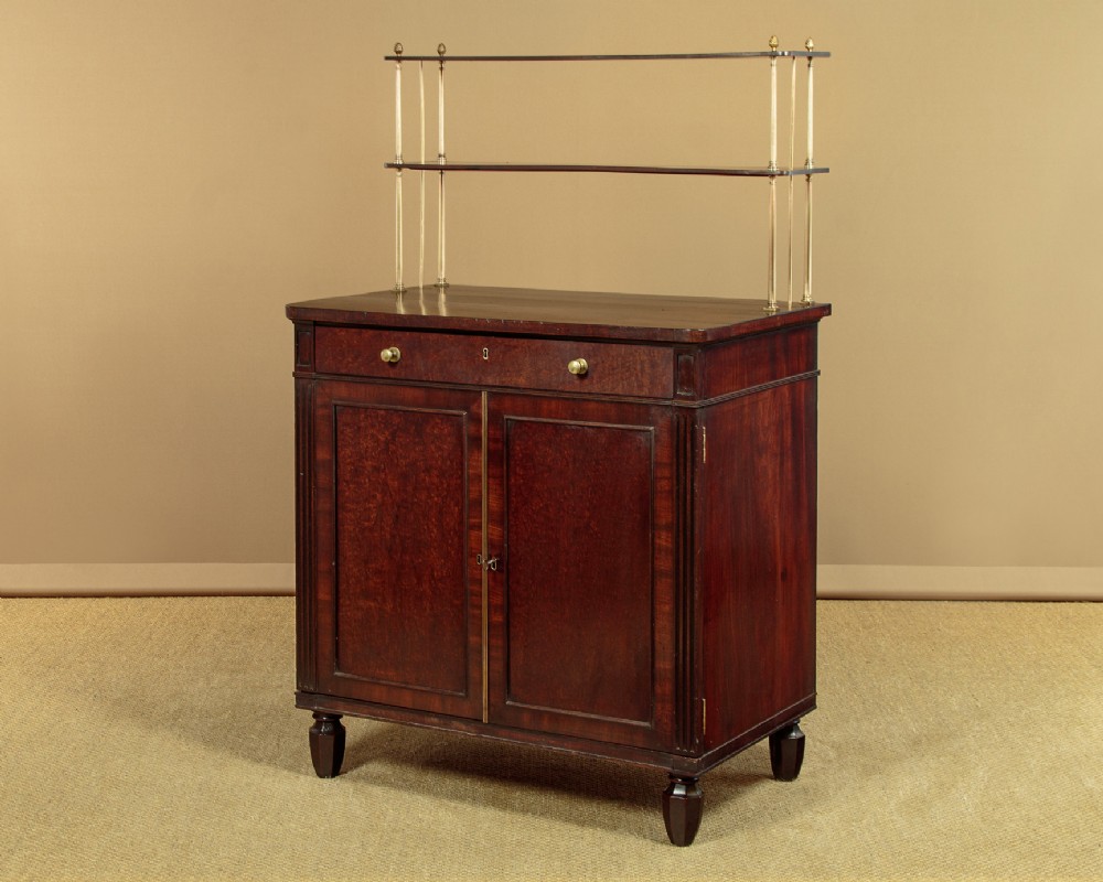 A Victorian mahogany chiffonier cabinet with a drawer, twin panelled cupboard doors, fluted pilasters, and a two-tiered brass-supported top shelf.