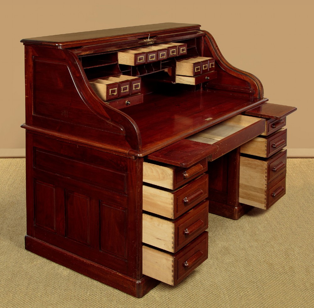 An Edwardian dark walnut roll top desk with a open slatted tambour shutter revealing interior drawers and pigeonholes above twin pedestal bases.