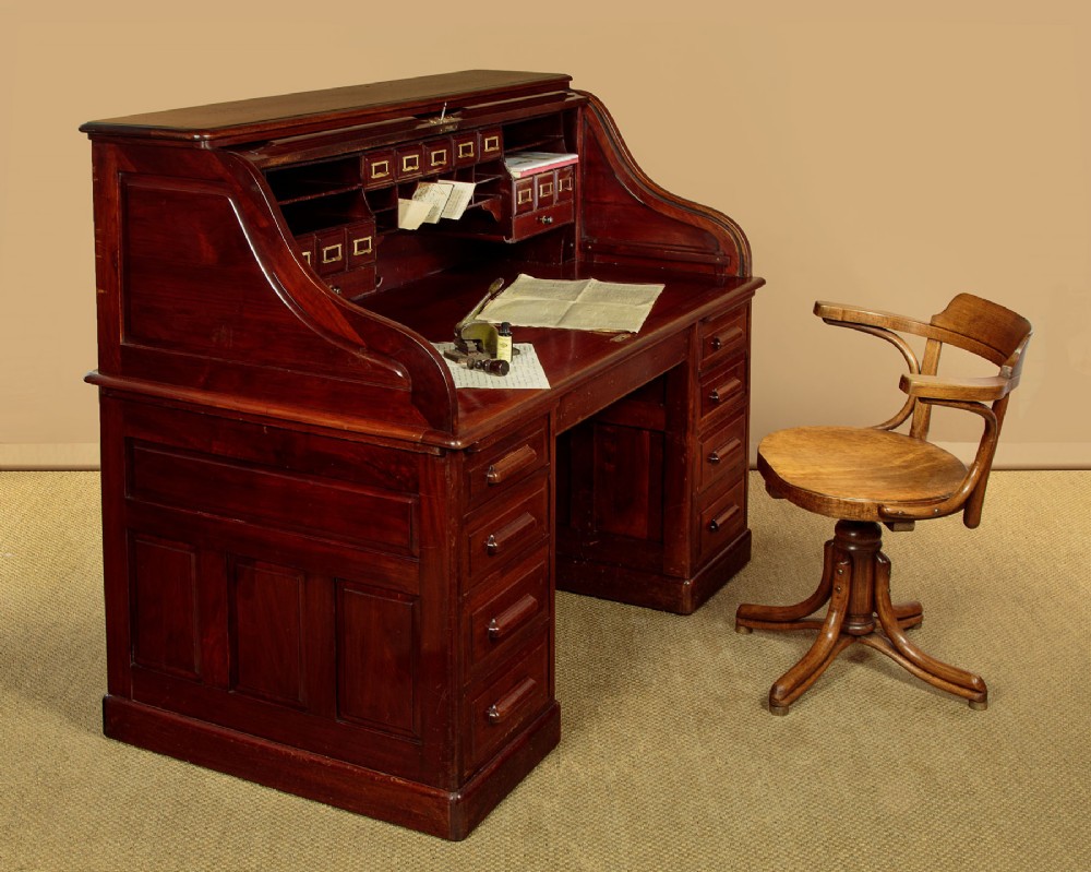 An Edwardian dark walnut roll top desk with a open slatted tambour shutter revealing interior drawers and pigeonholes above twin pedestal bases. View II