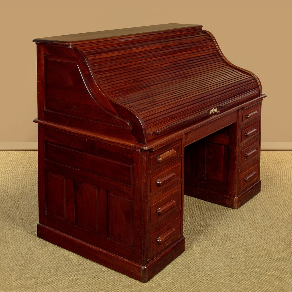 An Edwardian dark walnut roll top desk with a open slatted tambour shutter revealing interior drawers and pigeonholes above twin pedestal bases. View V