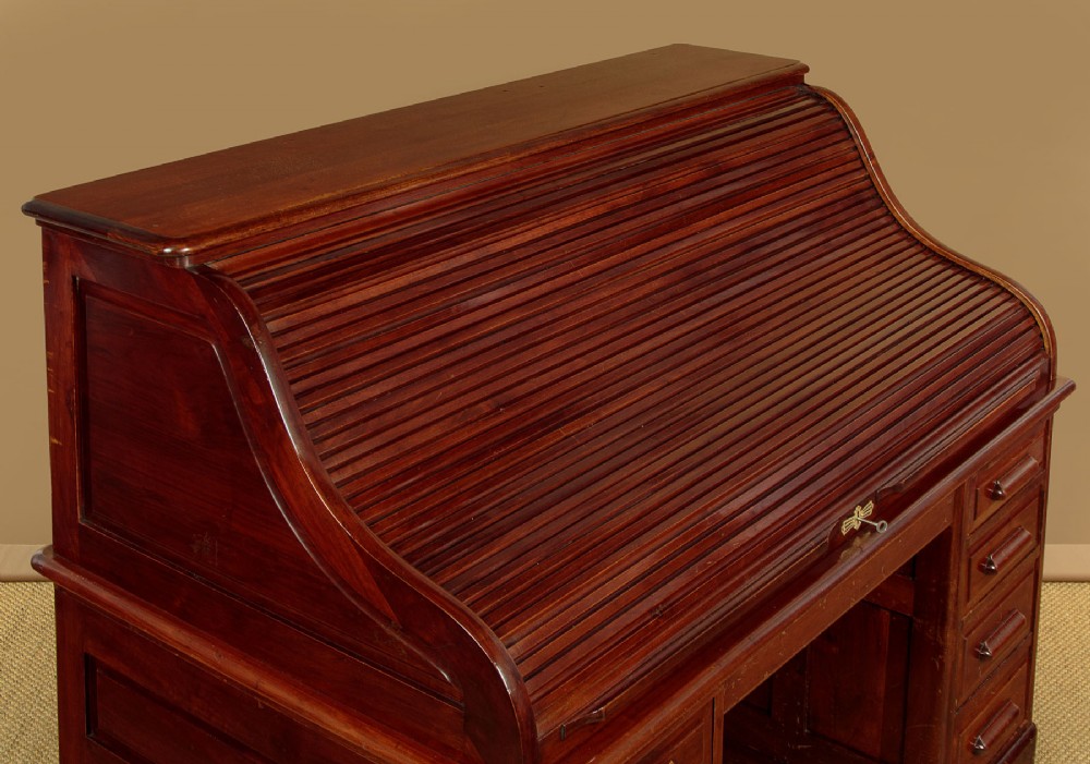 An Edwardian dark walnut roll top desk with a open slatted tambour shutter revealing interior drawers and pigeonholes above twin pedestal bases. View VI