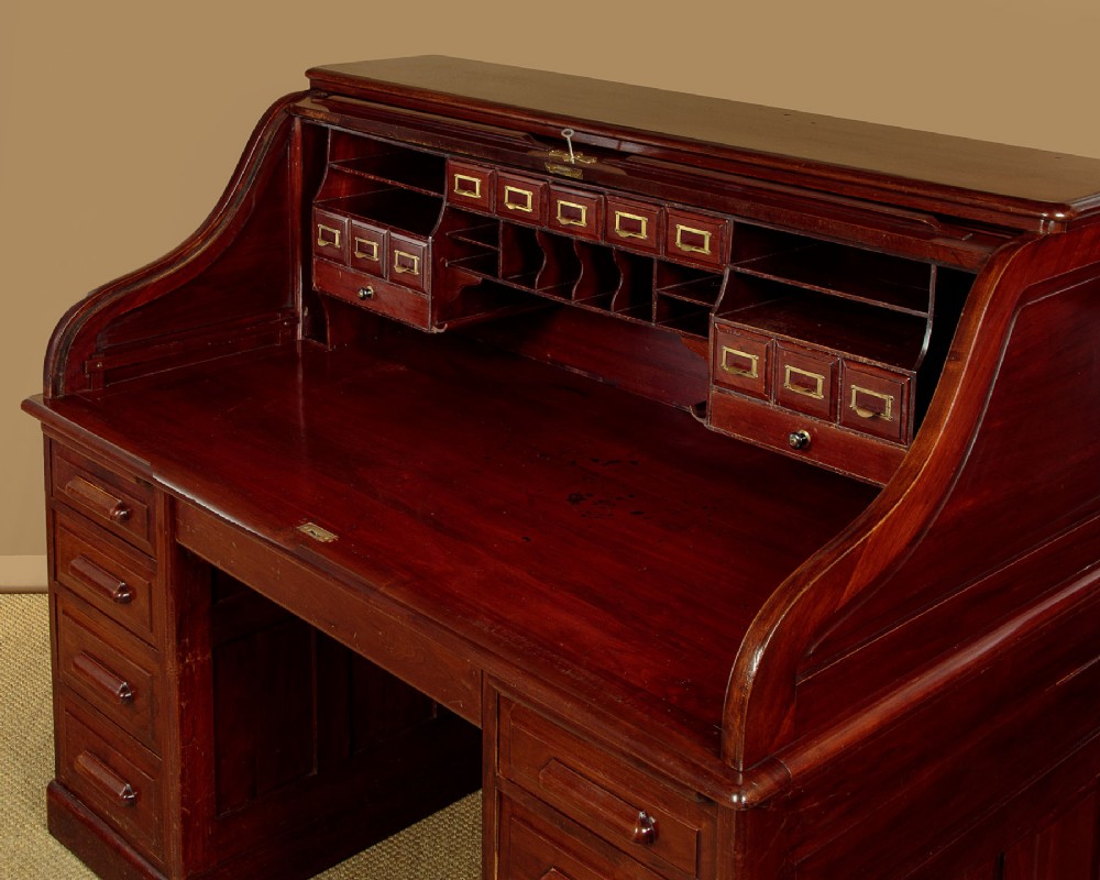 An Edwardian dark walnut roll top desk with a open slatted tambour shutter revealing interior drawers and pigeonholes above twin pedestal bases. View VII